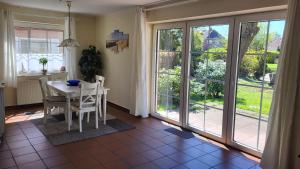a dining room with a table and chairs and sliding glass doors at Wohnung Karina in Krummhörn