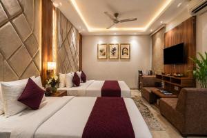 a hotel room with two beds and a television at Hotel Belwood De Near Delhi Airport IGI in New Delhi