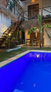 a blue swimming pool in front of a house at Pousada Vila do Alto in Japaratinga