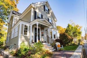 a white house with a porch and a chair at Antique Charmer Walk to Downtown KBK in Kennebunk