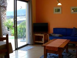 a living room with a couch and a tv and a window at Bungalows El Paradiso in Tazacorte
