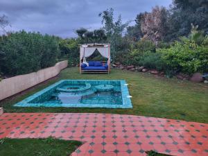 a pool with a chair and a tent in a yard at Lodgegarden in Aït Bounnit