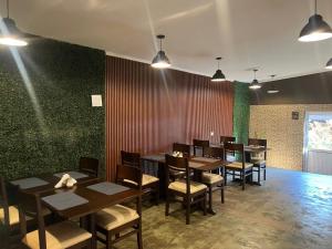a dining room with tables and chairs and a green wall at HOTEL BL in Puerto Iguazú