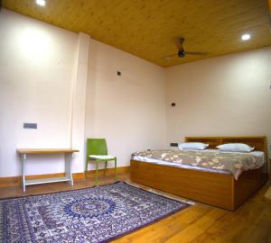 a bedroom with a bed and a table and a rug at MAHARANI Hotel in Khatīma