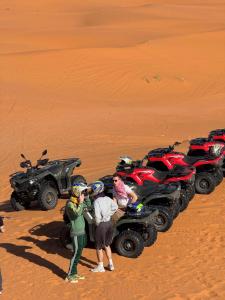 a group of people standing next to a atv in the desert at Hidden luxury Camp in Merzouga +23 photos
