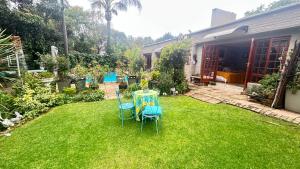 two chairs and a table in a yard at Artzy's Garden View 1km to Olivedale Clinic in Northriding