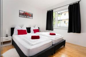 two beds in a bedroom with red and white pillows at Maisonette-Apartment mit großer Terrasse im Zentrum von Bregenz in Bregenz