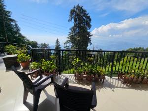 a balcony with chairs and potted plants and a fence at Smarthill-Green Forest View in Dalhousie