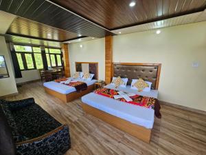 a hotel room with two beds and a chair at Smarthill-Green Forest View in Dalhousie