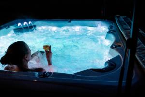 a woman in a hot tub with a glass of wine at Reetmeer Apartments Spa & Reetdach am Salzhaff in Boiensdorf