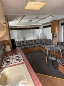 a kitchen with a stove and a sink and a table at Seaside Getaways Caravan Hire in Chapel Saint Leonards