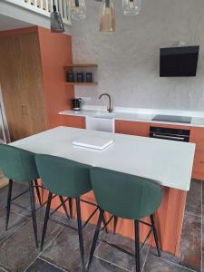a kitchen with a white counter and green chairs at Sunny Hills Cottage in Cornamona +22 photos
