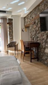 a bedroom with a table and a tv on a stone wall at Olympus Stone Lodge in Litochoro