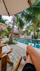 a person sitting on a chair next to a swimming pool at Nuevo NAYAL in Las Peñitas