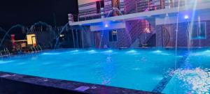 a large swimming pool with blue water at night at Kheya Tori Resort in Tajpur