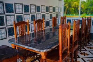 a dining room table with wooden chairs and a black table at Kheya Tori Resort in Tajpur