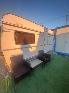 an rv with two chairs and a table in a yard at A little paradise 2 in Radanovići