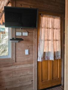a door with a television and a window with a curtain at La Chorrera ecohotel in Cocorná