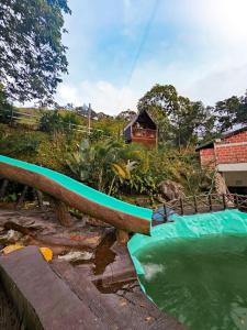 a pool of green water with a house in the background at La Chorrera ecohotel in Cocorná