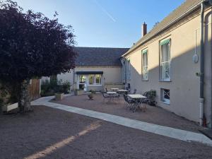 a patio with a table and chairs in front of a house at Logis Hôtel Restaurant Bar du Commerce - Maison Robin in Tronget