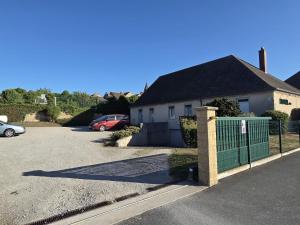 a house with a green fence in a parking lot at Logis Hôtel Restaurant Bar du Commerce - Maison Robin in Tronget