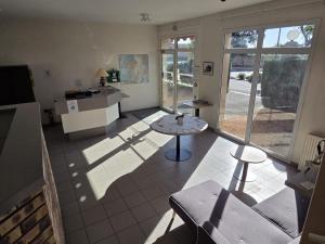 a living room with a table and a kitchen at Logis Hôtel Restaurant Bar du Commerce - Maison Robin in Tronget