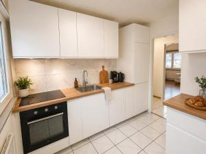 a kitchen with white cabinets and a sink at Topview 2BR Balcony & Mountain View Interlaken in Unterseen