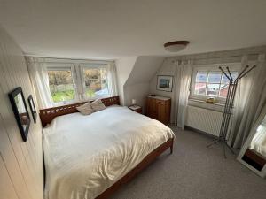 a bedroom with a bed with white sheets and two windows at Ferienhaus Husum Nordsee in Husum