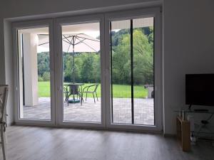 an open sliding glass door with a table and an umbrella at U Znajomych in Wołkowyja
