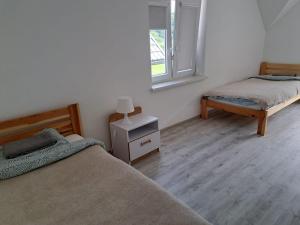 a bedroom with two beds and a lamp on a night stand at U Znajomych in Wołkowyja
