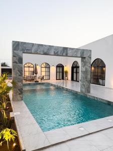 a large swimming pool with blue water in a building at Lava & Luna chalets in Sohar
