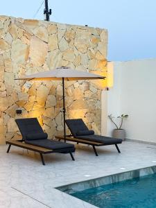two chairs and an umbrella next to a pool at Lava & Luna chalets in Sohar