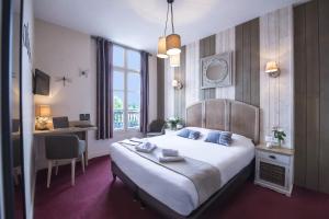 ein Hotelzimmer mit einem großen Bett und einem Schreibtisch in der Unterkunft Cristal Hôtel Restaurant in Saumur