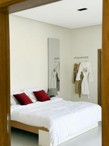 a white bedroom with a large bed with red pillows at Lava & Luna chalets in Sohar +40 photos