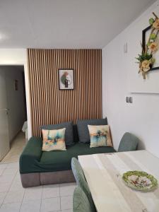 a living room with a green couch and a table at Apartments Villa Bazilika in Sečovlje