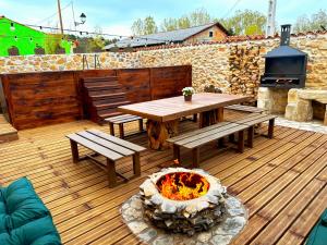 a wooden deck with a table and benches and a fire pit at El nido del Mirlo in Casarejos