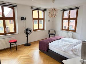 a bedroom with a bed and a fan and windows at Stilvolles Altstadt-Apartment in Bestlage in Dinkelsbühl