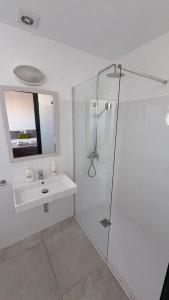 a white bathroom with a sink and a shower at Hostal Noray in Punta Prima