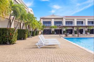 a pair of white chairs sitting in front of a building at Eagle Beach Cozy Condo in Palm-Eagle Beach