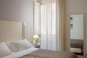 a white bedroom with a bed and a window at Altarocca Embassy Rome in Rome