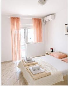 a white bedroom with two beds and a window at Vila Vukotić in Petrovac na Moru