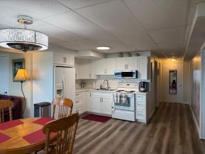 a kitchen with white cabinets and a table and a dining room at N' This on the Bay -Vacation Suite in Wiarton