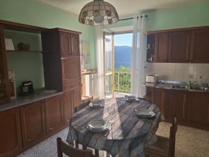 a kitchen with a table and a large window at La Cuccia del Sole Panoramische appartementen met zwembad in Cortemilia