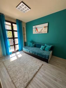 a living room with a couch in a blue wall at Balaton Vibe Apartman Füred in Balatonfüred