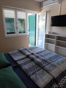a bed in a room with a tv and windows at Villa Olma in Okrug Gornji +55 photos