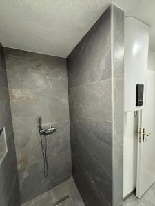 a shower in a bathroom with a gray wall at Apartman Ljiljan in Sanski most +6 photos