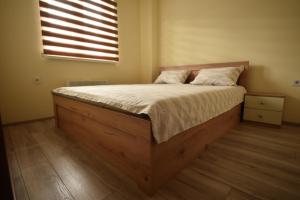 a bed with a wooden frame in a bedroom with a window at Apartman Valentina Aqua Park in Jagodina
