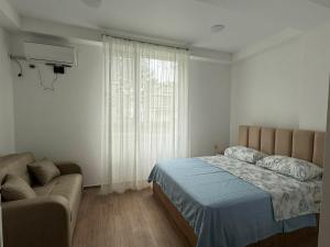 a bedroom with a bed and a couch and a window at Grigoleti Royal in Grigoleti