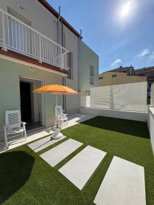 eine Terrasse mit Sonnenschirm und Rasen in der Unterkunft Dimora Caprera - Appartamenti in Falconara Marittima + 73 Fotos