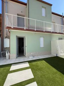 ein Haus mit Balkon und Rasenhof in der Unterkunft Dimora Caprera - Appartamenti in Falconara Marittima